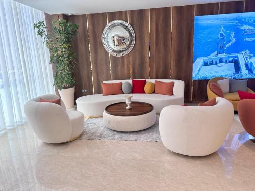 a living room with three white couches and a table at 2H Hotel in Oran
