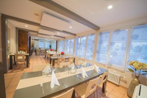 a dining room with tables and chairs and windows at Logis Hôtel Restaurant Barrey in Orchamps-Vennes