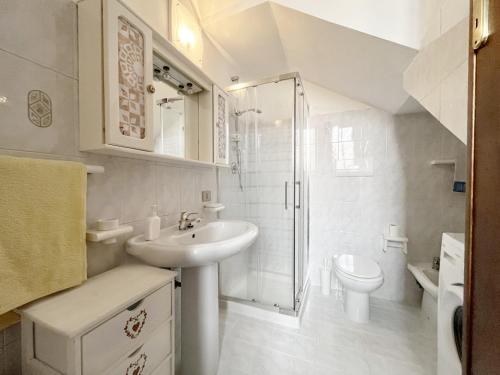 een witte badkamer met een wastafel en een douche bij Casa Lia - Independent apartment in the Gulf of Orosei in Galtellì