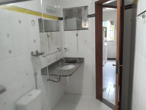 a white bathroom with a sink and a shower at Apt. aconchegante Melhor Localização do Centro: conforto e praticidade in Porto Seguro