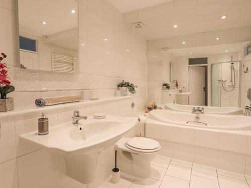 uma casa de banho branca com 2 lavatórios e um WC em White Sails em Y Felinheli