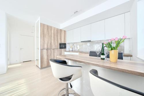 a kitchen with white cabinets and a counter with chairs at ApartamentyPrzyMorzu Strzelecka 33 z parkingiem in Kołobrzeg