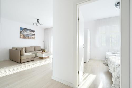 a white living room with a couch and a mirror at ApartamentyPrzyMorzu Strzelecka 33 z parkingiem in Kołobrzeg