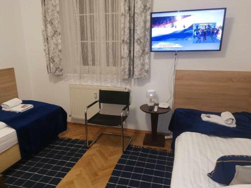 a room with two beds and a tv on the wall at Eisenerzer Apartments - Radmeisterhaus in Eisenerz