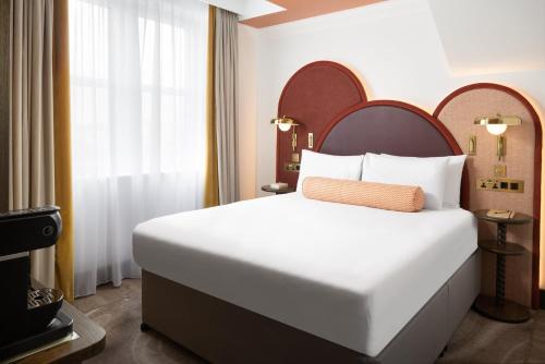 una camera da letto con un grande letto bianco e una finestra di Holiday Inn London Oxford Circus, an IHG Hotel a Londra