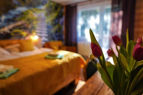 Hotel Raj في ديدينكي: مزهرية من زهور الأقحوان الحمراء تجلس بجانب طاولة