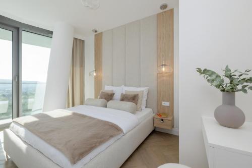 a white bedroom with a large bed and a window at Wave Międzyzdroje Luxury Apartment MORENORENT in Międzyzdroje