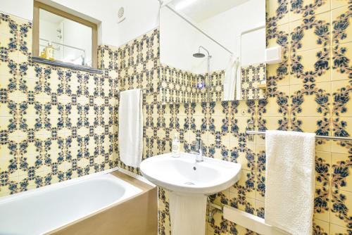 a bathroom with yellow and blue tiled walls and a sink at Casa dos Avós in Albufeira