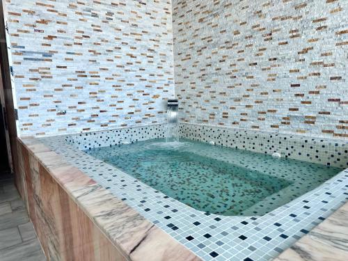 a bath tub in a bathroom with a tile wall at 2H Hotel in Oran