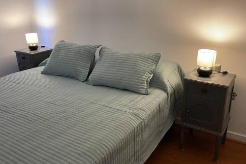 Una cama con dos mesitas de noche con dos lámparas. en Recién renovado! Elegancia y comodidad en Bellavista en Santiago