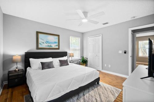 a bedroom with a large white bed with a ceiling fan at Peaceful Pearl Retreat- 5 Minutes to Downtown, 10 Minutes to Beach in Saint Augustine
