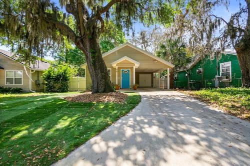 a house with a tree in front of a driveway at Peaceful Pearl Retreat- 5 Minutes to Downtown, 10 Minutes to Beach in St. Augustine