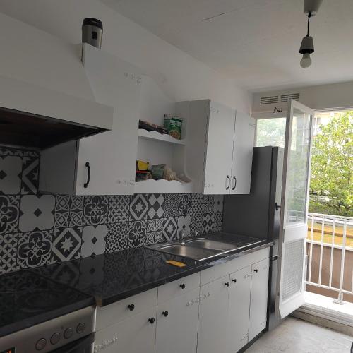 une cuisine avec des placards blancs et un comptoir noir dans l'établissement Chambre d'hôtes appartement en colocation, à Rennes
