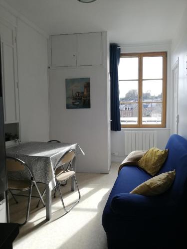 un salon avec un canapé bleu et une table dans l'établissement Petit appartement en bord 2 mer., à Veules-les-Roses