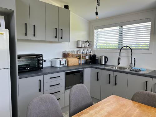 a kitchen with white cabinets and a table with chairs at Hills Vista Lodge in Matamata