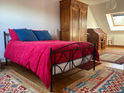 um quarto com uma cama com um cobertor rosa e uma cómoda em Le Poulailler em Loué