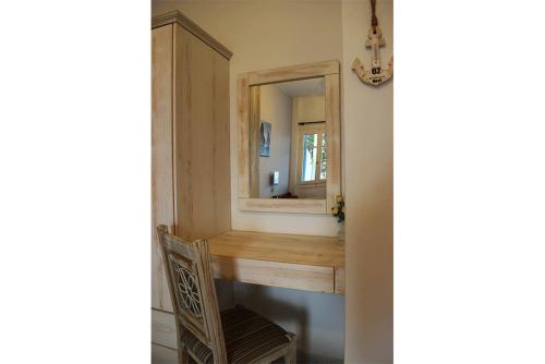 uma casa de banho com um toucador, um espelho e uma cadeira. em Κalamitsi Rooms & Apartments em Kimolos