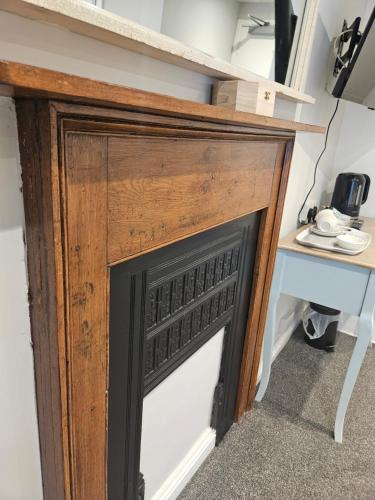 a wooden fireplace in a room with a desk at The Beacons Guest House in Brecon