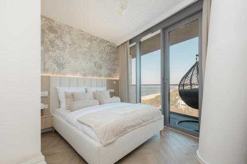 1 dormitorio con 1 cama blanca grande y ventanas grandes en Wave Międzyzdroje Sea and Molo View MORENORENT, en Międzyzdroje