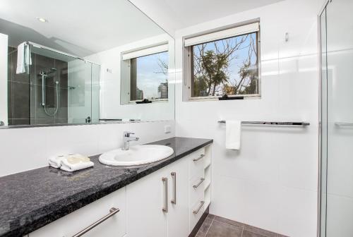 a white bathroom with a sink and a shower at Bridgewater Terraces in Brisbane