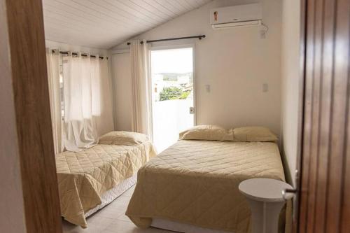 a small bedroom with two beds and a window at Amplo apto próximo a Praia in Garopaba