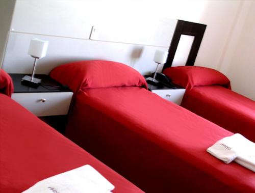 a room with two red beds and a desk at Nuevo Mundo in San Rafael