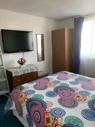a bedroom with a bed and a flat screen tv at Hospedaje Familiar Glady's House in Puerto Montt