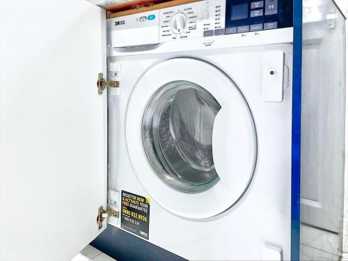 a white washing machine is in a room at 4 Bedrooms Homely House with Garden- Sleeps 9 Comfortably with 6 Comfortable Beds, Free Street Parking, Business Travellers, Contractors, & Holiday-Goers, Coventry, Near All Major Transport Links in Coventry and Motorway in Coventry