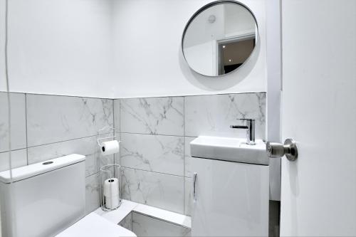 a white bathroom with a sink and a mirror at 4 Bedrooms Homely House with Garden- Sleeps 9 Comfortably with 6 Comfortable Beds, Free Street Parking, Business Travellers, Contractors, & Holiday-Goers, Coventry, Near All Major Transport Links in Coventry and Motorway in Coventry