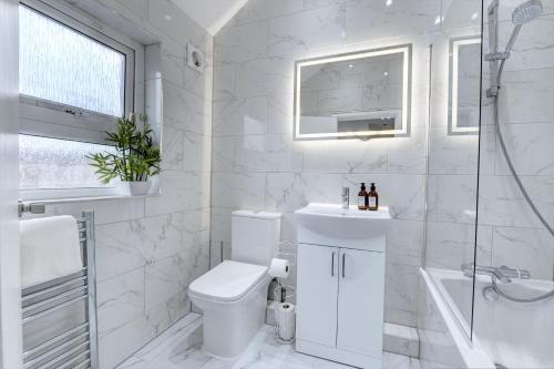 a white bathroom with a toilet and a sink at 4 Bedrooms Homely House with Garden- Sleeps 9 Comfortably with 6 Comfortable Beds, Free Street Parking, Business Travellers, Contractors, & Holiday-Goers, Coventry, Near All Major Transport Links in Coventry and Motorway in Coventry