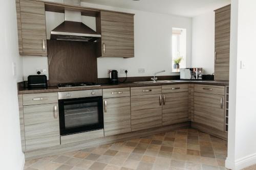 a kitchen with wooden cabinets and a stove top oven at Golden Flatts Apartment in Hartlepool