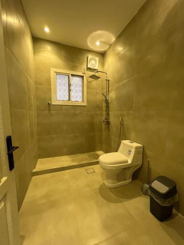 a bathroom with a toilet and a window at الركن الهادئ in Al Ḩawīyah