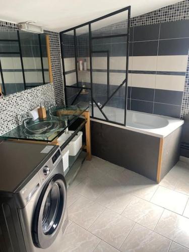 QuaroubleにあるAgréable maison avec parking gratuitのバスルーム(洗濯機、バスタブ付)