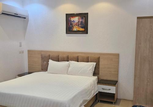 a bedroom with a white bed with a picture on the wall at نور المنازل للوحدات السكنية in Qarār