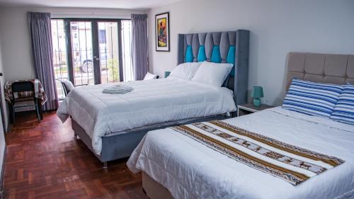 a hotel room with two beds and a balcony at Esmeralda Suite in Cusco