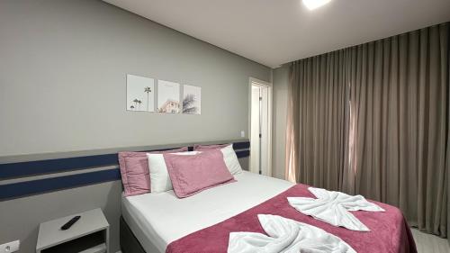a bedroom with a bed with pink and white sheets at 14- Studio decorado com ótima localização!!! in Curitiba