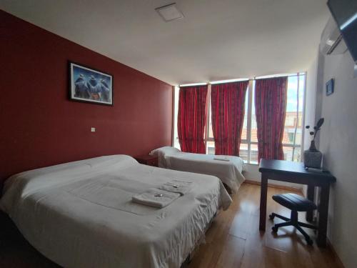 a bedroom with two beds and a table and a window at Hotel Ery Noa in San Salvador de Jujuy