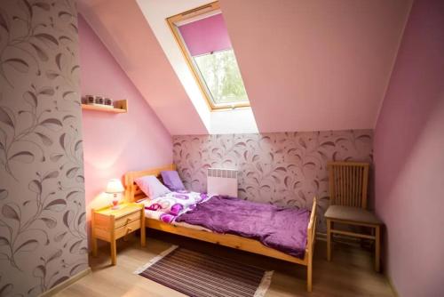 a bedroom with a purple bed in a attic at Domek A 142 Lawendowy- Kaszubska Ostoja in Barkocin