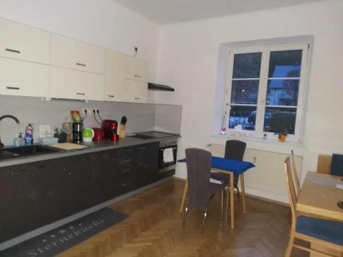 a kitchen with white cabinets and a table and chairs at Eisenerzer Apartments - Radmeisterhaus in Eisenerz
