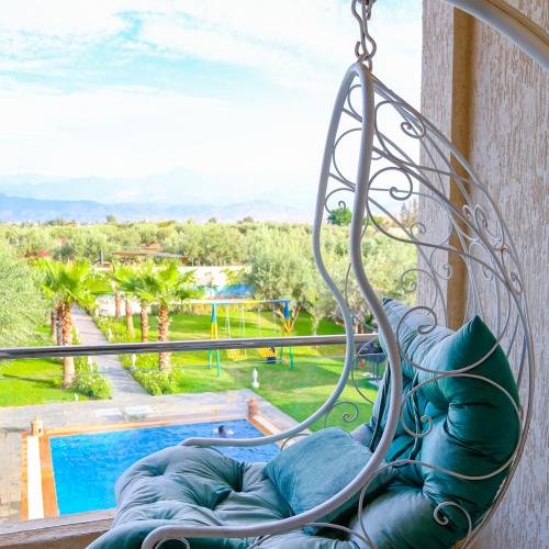 - une balançoire sur un balcon avec vue sur la piscine dans l'établissement Hotel Jnane riad, à Marrakech