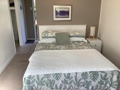 a bedroom with a bed with a green and white comforter at Wood Pigeon Cottage Pet Friendly Free Breakfast Hauraki Rail Trail 2kms in Waikino