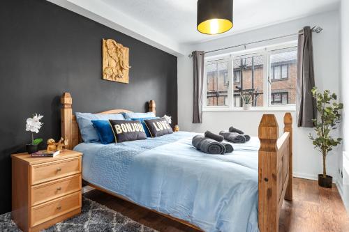 a bedroom with a blue bed and a window at Quirky Canary 2Bed, Free Parking, Smart TV & Games in London