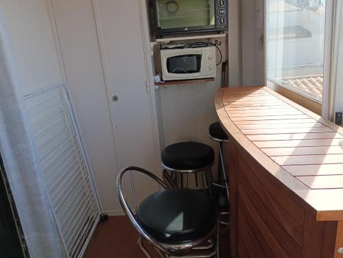 une cuisine avec deux tabourets et un comptoir avec un four micro-ondes dans l'établissement Plage, port, Cap d'Agde, au Cap d'Agde