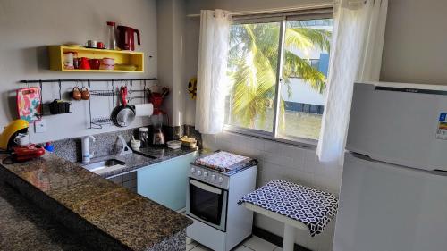 a small kitchen with a white refrigerator and a window at Ed Bertholi - Frente ao mar com garagem in Serra