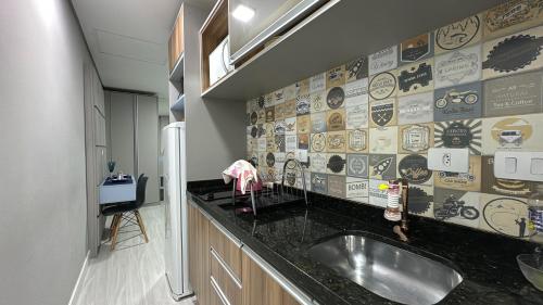 a kitchen with a sink and a wall with stickers at 16- Studio Decorado perfeito para casal!!! in Curitiba