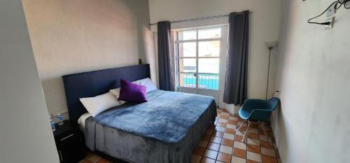 a bedroom with a bed with purple pillows and a window at Hotel Tao in Atlixco