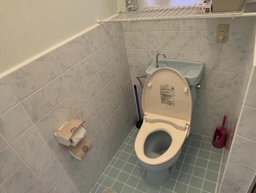a bathroom with a toilet and two rolls of toilet paper at Okinawa Naha JinJin -沖縄伝統体験型宿じんじん- in Naha