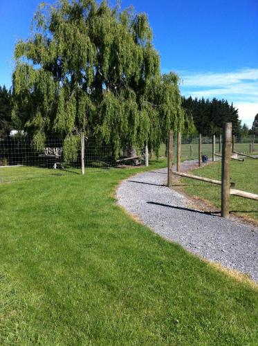 a path in a field with a fence and a tree at The Meadows Villa in Christchurch
