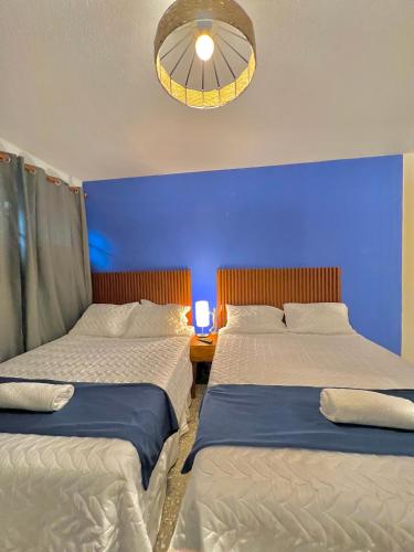 two beds in a bedroom with a blue wall at Hotel Citadin Z10 in Guatemala