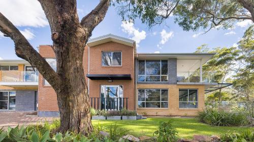 a brick house with a tree in front of it at Woodlands Sunsets Soldiers Point - Whole Property in Soldiers Point